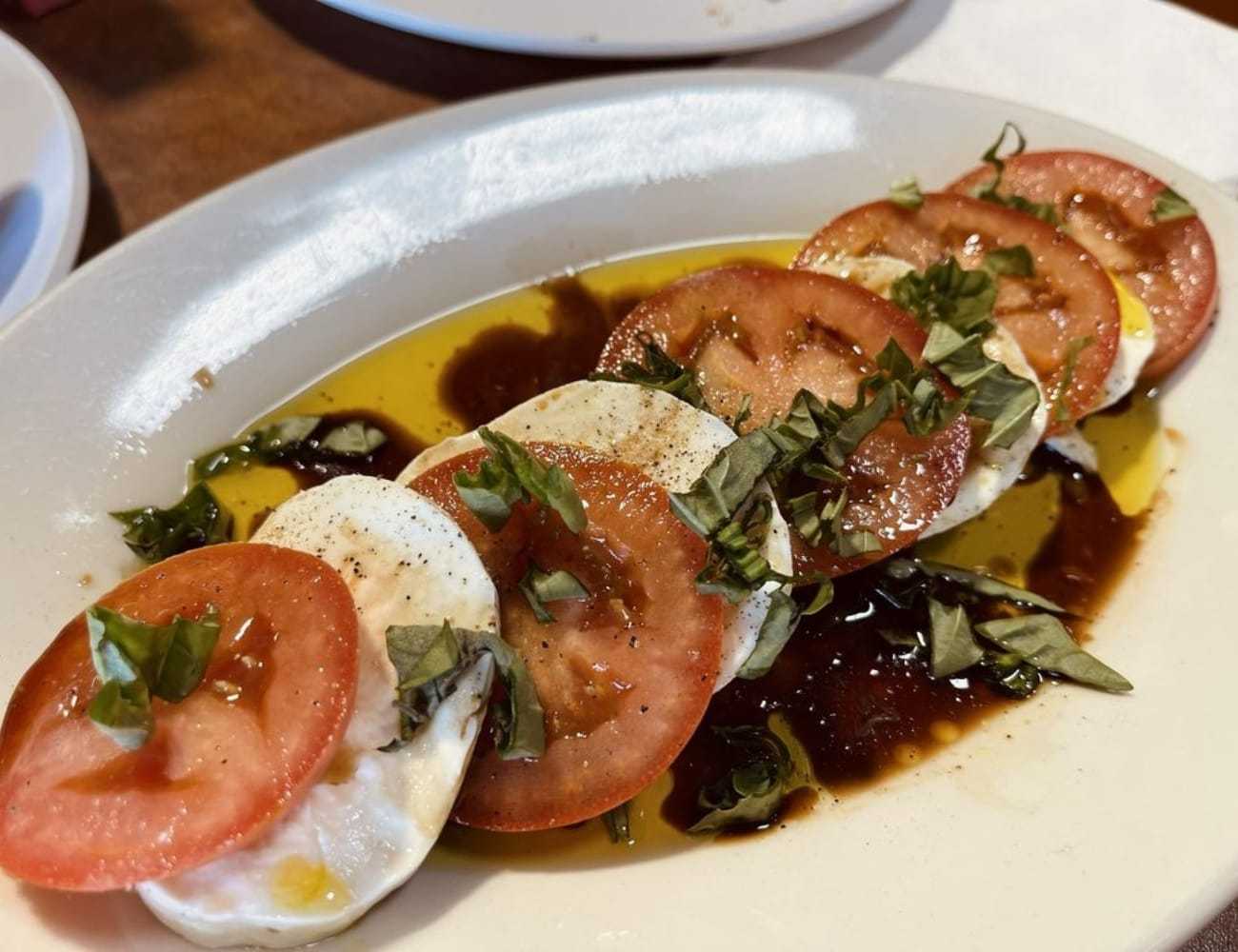 Caprese salad with fresh tomatoes, mozzarella, basil, olive oil, and balsamic vinegar.