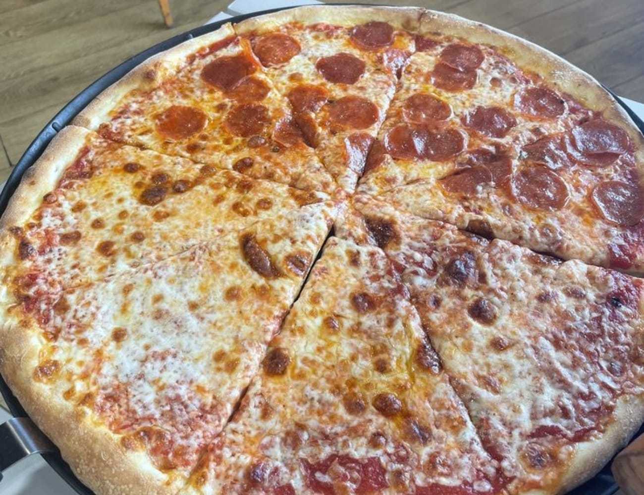 Cheese and pepperoni pizza on a round tray with a wooden floor background.